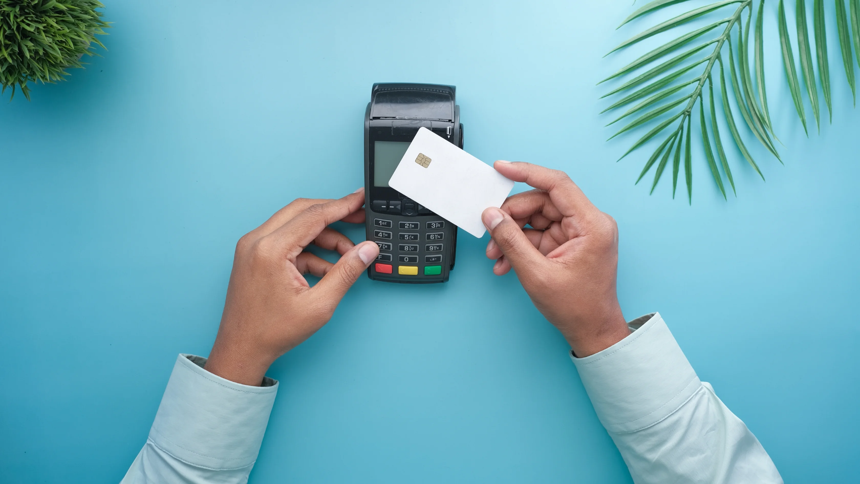 Hands holding a payment card over a countertop terminal