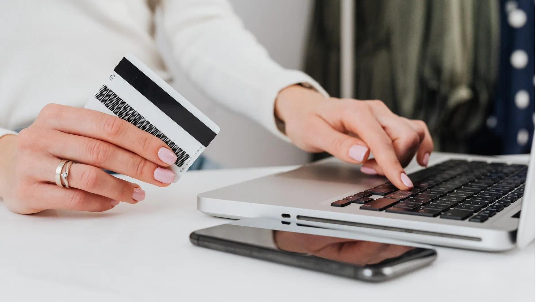 A shopper holding a card beside a laptop while checking out online